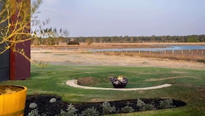 A landscaped outdoor area with a fire pit, a pond, and a building in the background. - Samphire Chalet Tuart—Luxury Amidst Nature (Busselton)