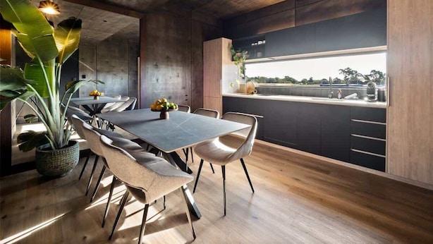 A modern dining area with a long table, chairs, and a potted plant. - Samphire Chalet Tuart—Luxury Amidst Nature (Busselton)