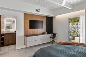 Ein modernes Schlafzimmer mit einem Bett, einem Schreibtisch und einem an der Wand befestigten Fernseher.