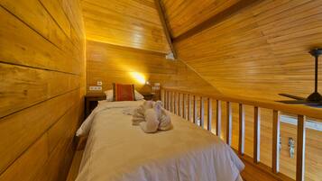 A cozy wooden cabin room with a bed, a nightstand, and a lamp.