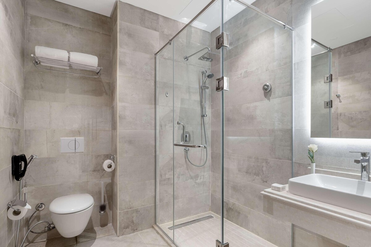 Une salle de bain moderne avec une douche à parois de verre, des toilettes, un lavabo et un porte-serviettes.