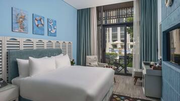 A hotel room with a large bed, a desk, a chair, and a view of the outdoor area.