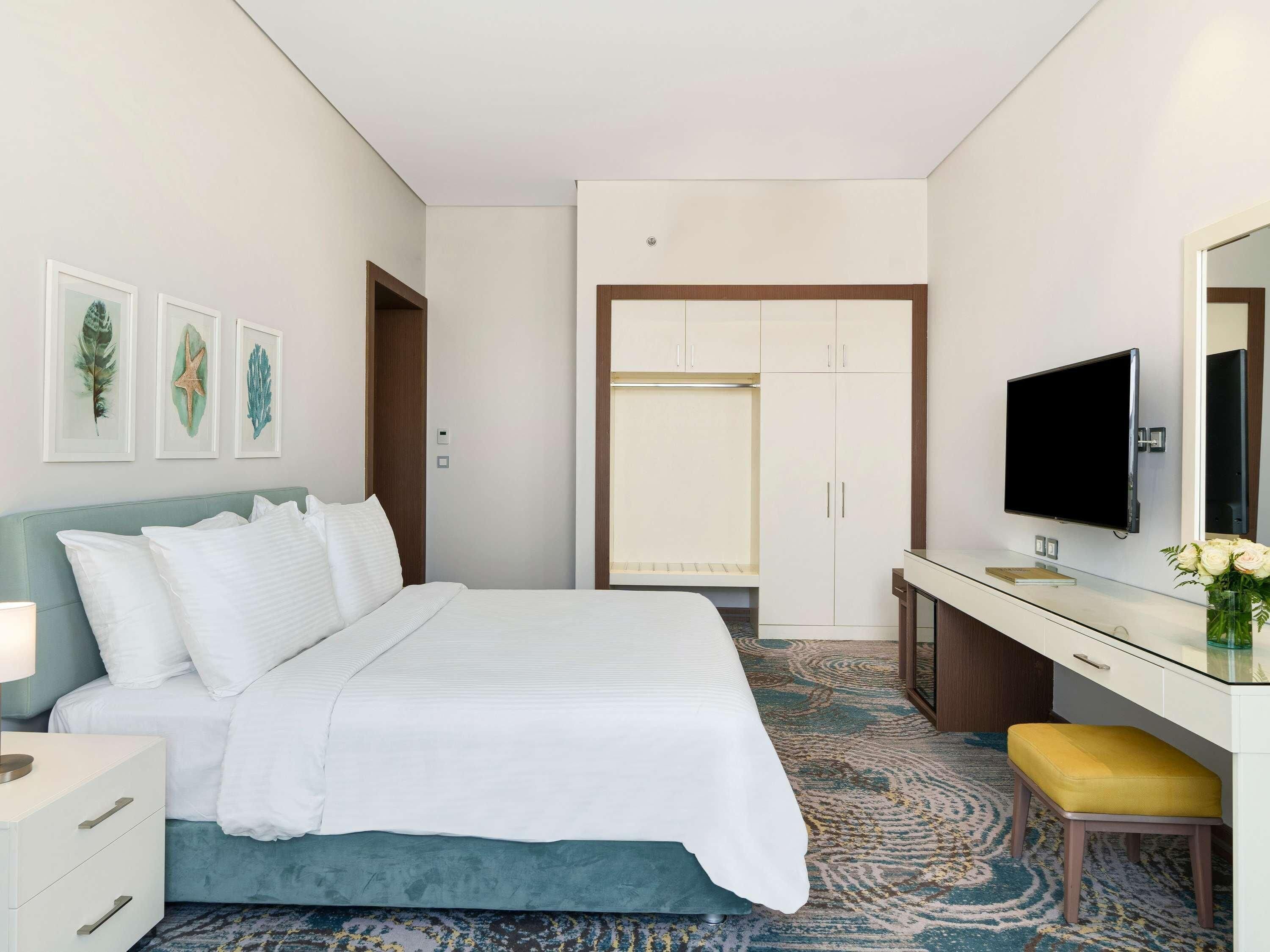 Une chambre d’hôtel équipée d’un lit, d’un bureau, d’une télévision et d’une armoire.