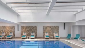 Un espace piscine avec des chaises longues et un mur en pierre en arrière-plan.