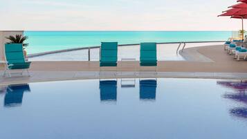 A poolside area with lounge chairs and a view of the ocean.