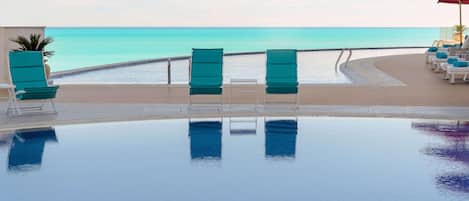 A poolside area with lounge chairs and a view of the ocean.