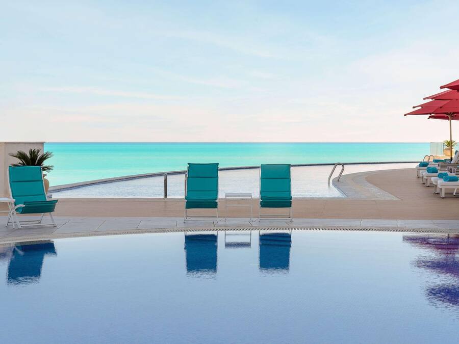 A poolside area with lounge chairs and a view of the ocean.