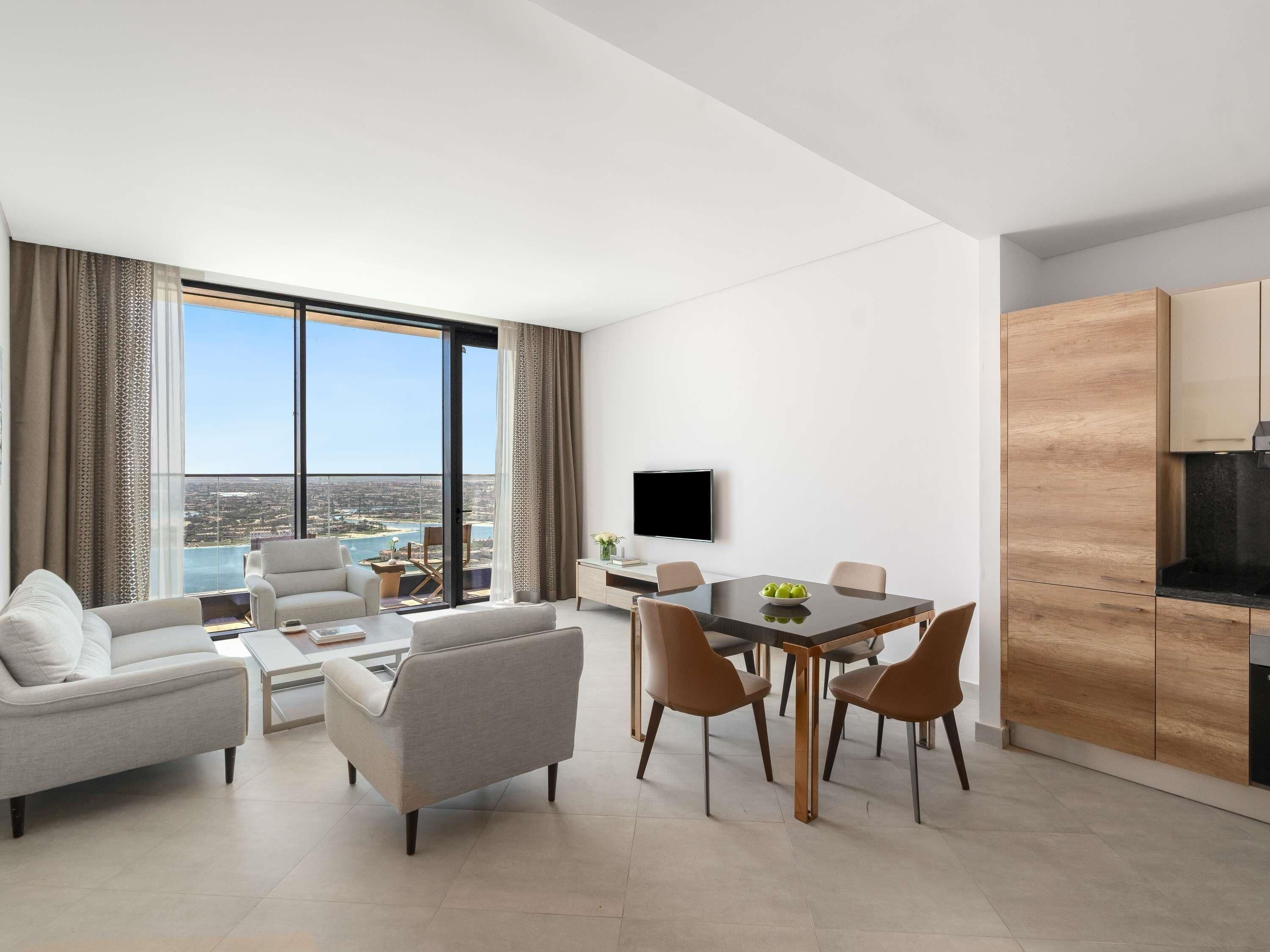 Un salon moderne comprenant un coin repas, un téléviseur à écran plat et une vue sur la ville.