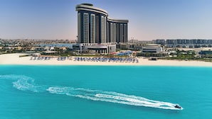 A coastal hotel with a beachfront, a large building with vertical lines, and a clear blue sea. - Rixos Premium Alamein (El Alamein)