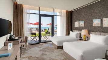Une chambre d’hôtel avec deux lits, un bureau, une télévision et un balcon agrémenté de parasols rouges.