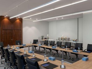 A conference room with long tables, black chairs, water bottles, and tissue boxes.