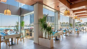 A modern dining area with tables, chairs, and hanging lights.