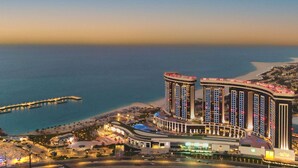 A high-rise hotel with multiple floors, a pool, and a beach view. - Rixos Premium Alamein (El Alamein)