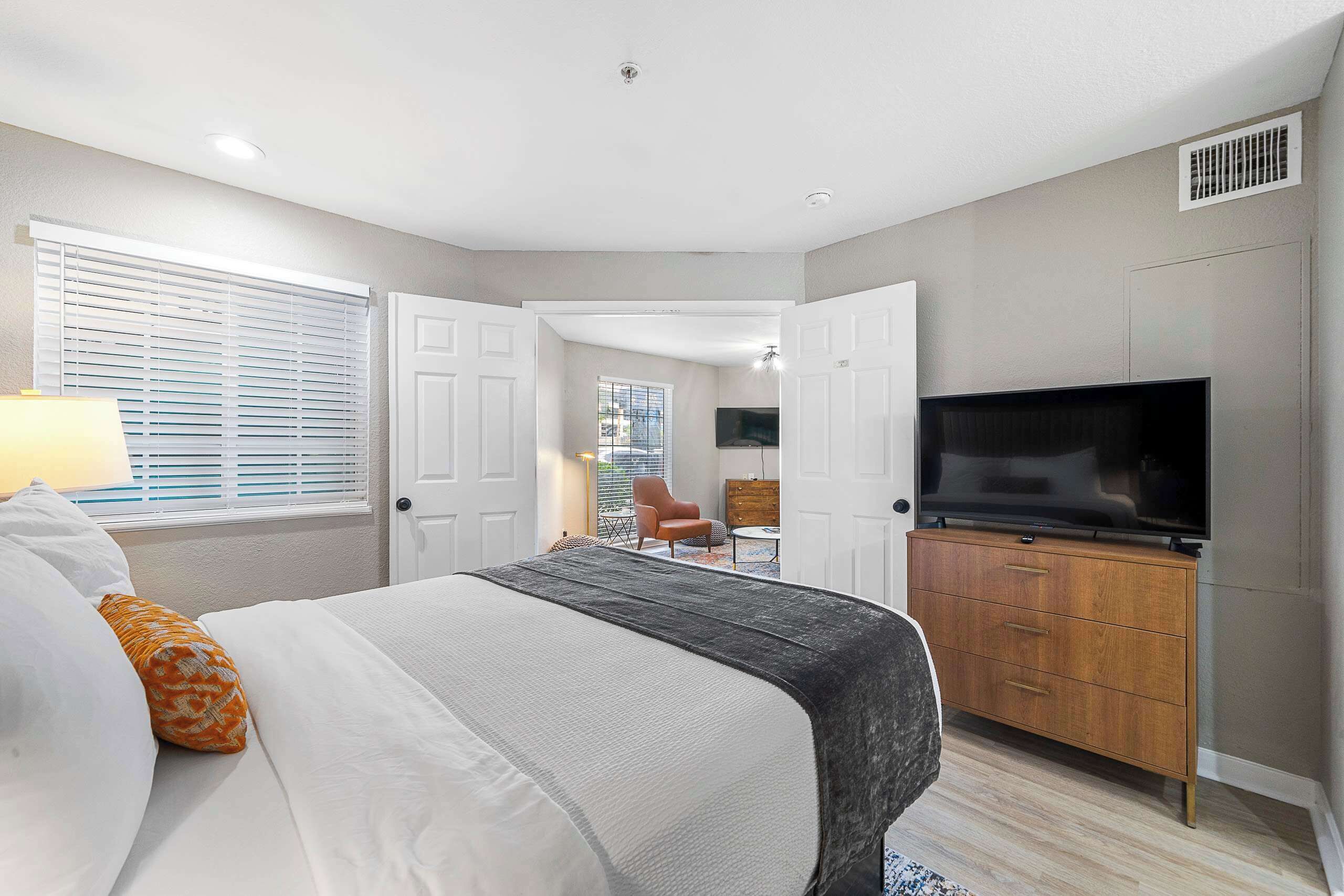 Een slaapkamer met een bed, een televisie, een dressoir en een stoel.