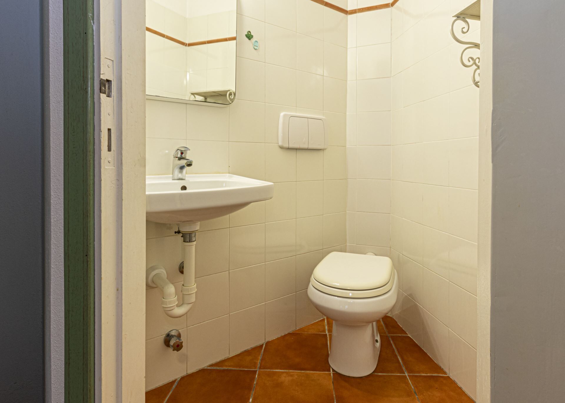 A bathroom with a white sink, a toilet, and a mirror.