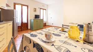Eine Küche mit Kühlschrank, Herd und einem Esstisch mit einem Tischlein mit Fischmuster.