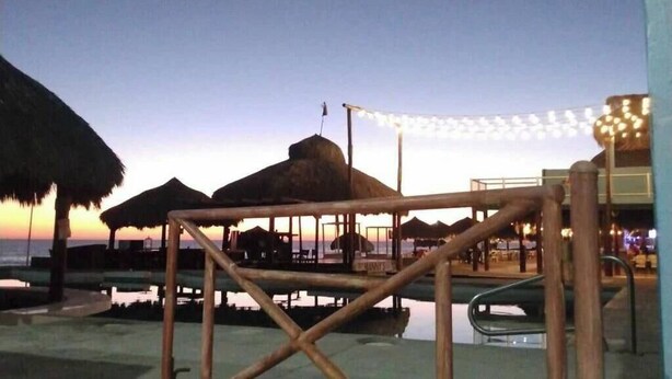 A beachside resort with thatched umbrellas, a pool area, and string lights. - Condo Mirador with Rooftop Ramada Near Sea of Cortéz, El Malecon, and Manny's. (Puerto Peñasco)