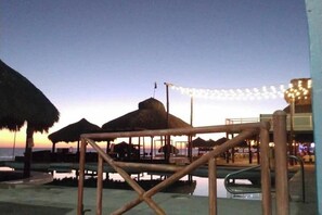 A beachside resort with thatched umbrellas, a pool area, and string lights. - Condo Mirador with Rooftop Ramada Near Sea of Cortéz, El Malecon, and Manny's. (Puerto Peñasco)