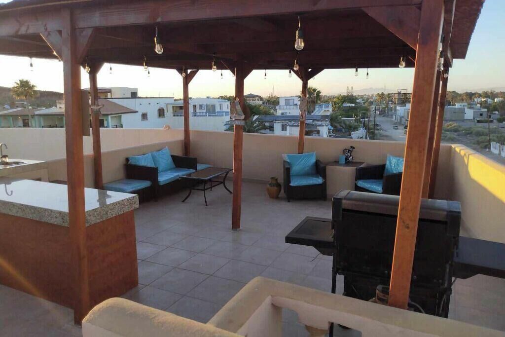 Une terrasse sur le toit avec un espace bar, des sièges et une vue sur le paysage urbain.