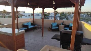 Une terrasse sur le toit avec un espace bar, des sièges et une vue sur le paysage urbain.