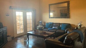A living room with a leather sofa, a coffee table, and a large mirror on the wall. - Condo Mirador with Rooftop Ramada Near Sea of Cortéz, El Malecon, and Manny's. (Puerto Peñasco)