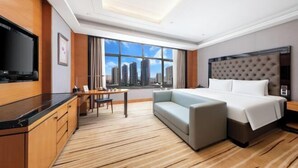 A hotel room with a large bed, a TV, a desk, and a view of tall buildings. - S&N Hotel Changzhou (Changzhou)