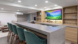 Eine moderne Küche mit Barbereich, Barhocker und einem großen Flachbildfernseher.