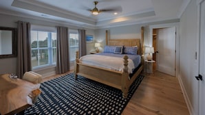 Ein geräumiges Schlafzimmer mit einem großen Bett, einem Deckenventilator und Blick ins Freie durch das Fenster.