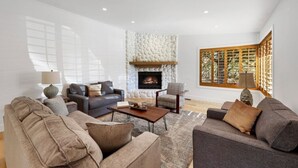 A spacious living room with a stone fireplace, comfortable seating, and large windows. - Summit Lodge- Sleeps 10, 4 Full Bath, Pet Friendly (Prescott)