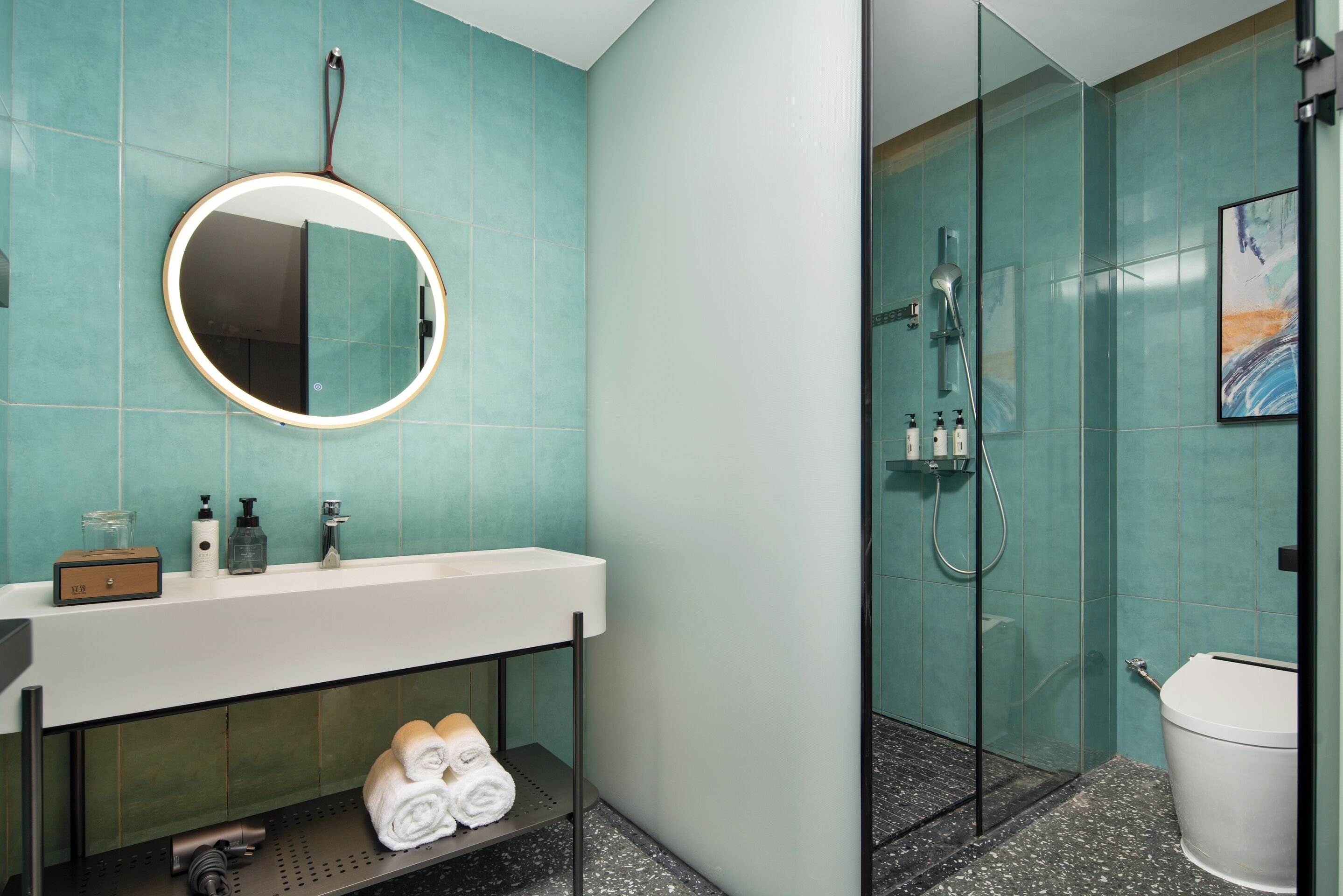A bathroom with a round mirror, a sink, and a shower area.