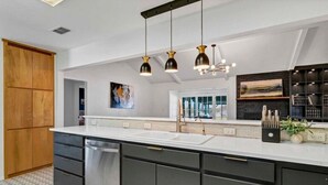 A modern kitchen with dark cabinetry, a white countertop, and pendant lighting.
