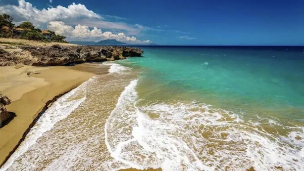 A beach with clear turquoise water, sandy shore, and rocky outcrops. - Crea recuerdos inolvidables en este alojamiento único y familiar. (Sosúa)