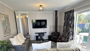 A modern living room with a grey sofa, a flat-screen TV, a fireplace, and a large window.
