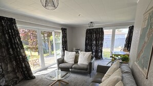 A modern living room with a grey sofa, a glass coffee table, and a ceiling fan.