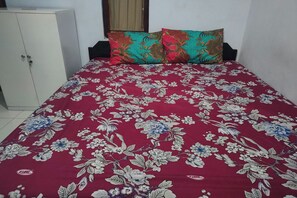 A bed with a floral bedspread, a wardrobe, and a window with curtains. - Homestay Wijaya Mulya By Zuzu (Borobudur)