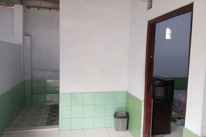 A small, sparsely furnished room with a tiled floor, a trash bin, and a television in the corner. - Homestay Wijaya Mulya By Zuzu (Borobudur)