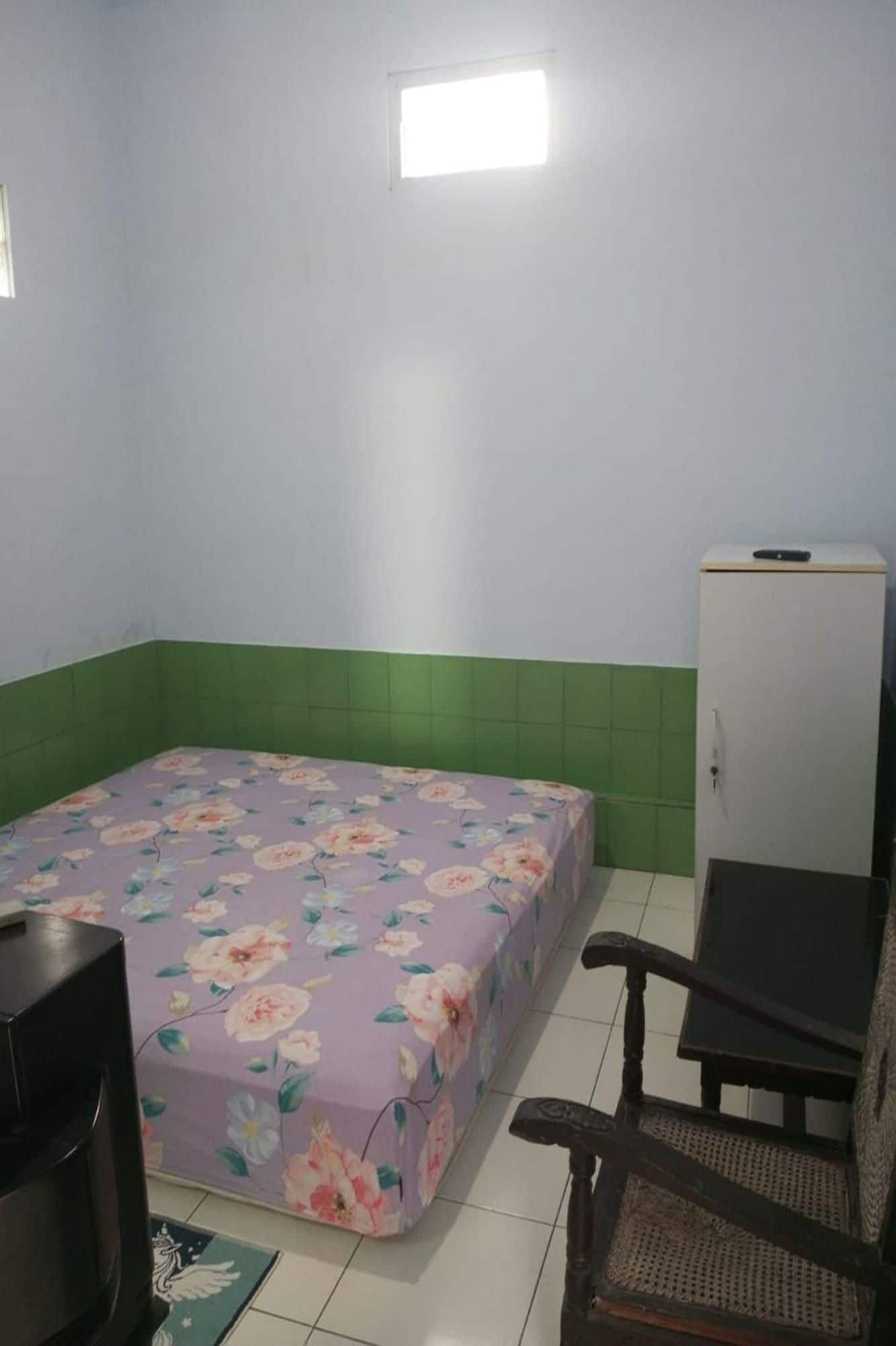 Una habitación pequeña con una cama, una silla, un televisor y un armario.