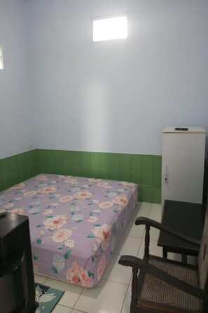 A small room with a bed, a chair, a television, and a cabinet. - Homestay Wijaya Mulya By Zuzu (Borobudur)