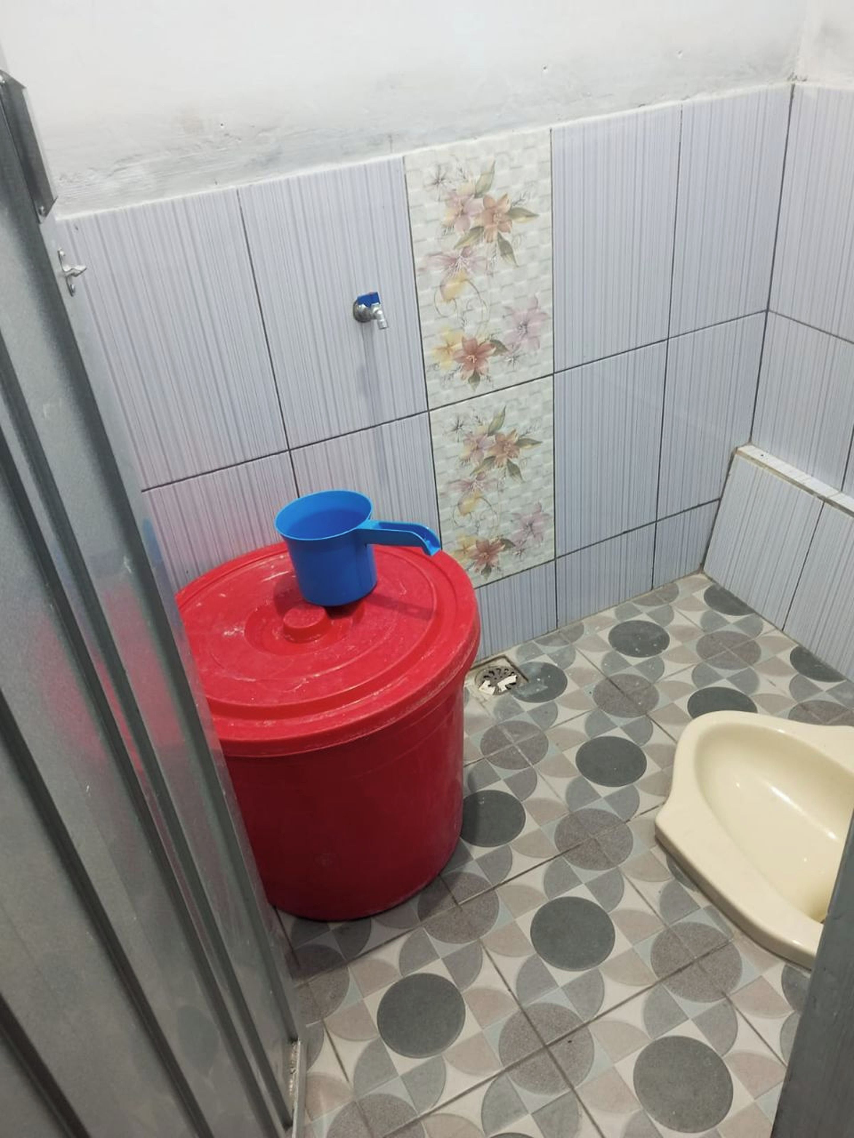 Un bagno piccolo con un water, un cestino rosso e un rubinetto fissato alla parete.