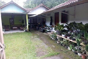 A covered outdoor area with a seating arrangement and a variety of potted plants. - Homestay Wijaya Mulya By Zuzu (Borobudur)