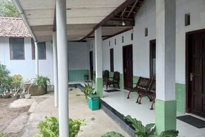A covered porch with chairs and a bench, a tiled floor, and potted plants. - Homestay Wijaya Mulya By Zuzu (Borobudur)