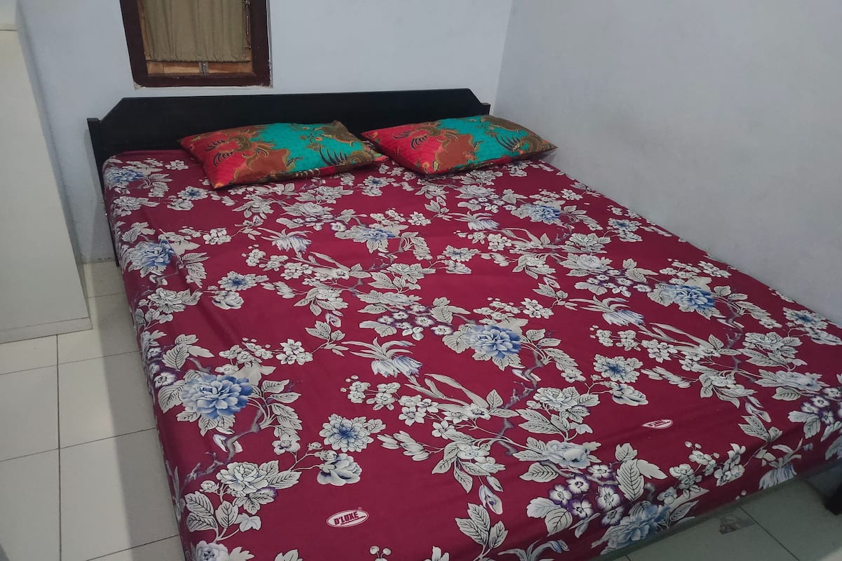 A bed with a floral bedspread and two pillows.