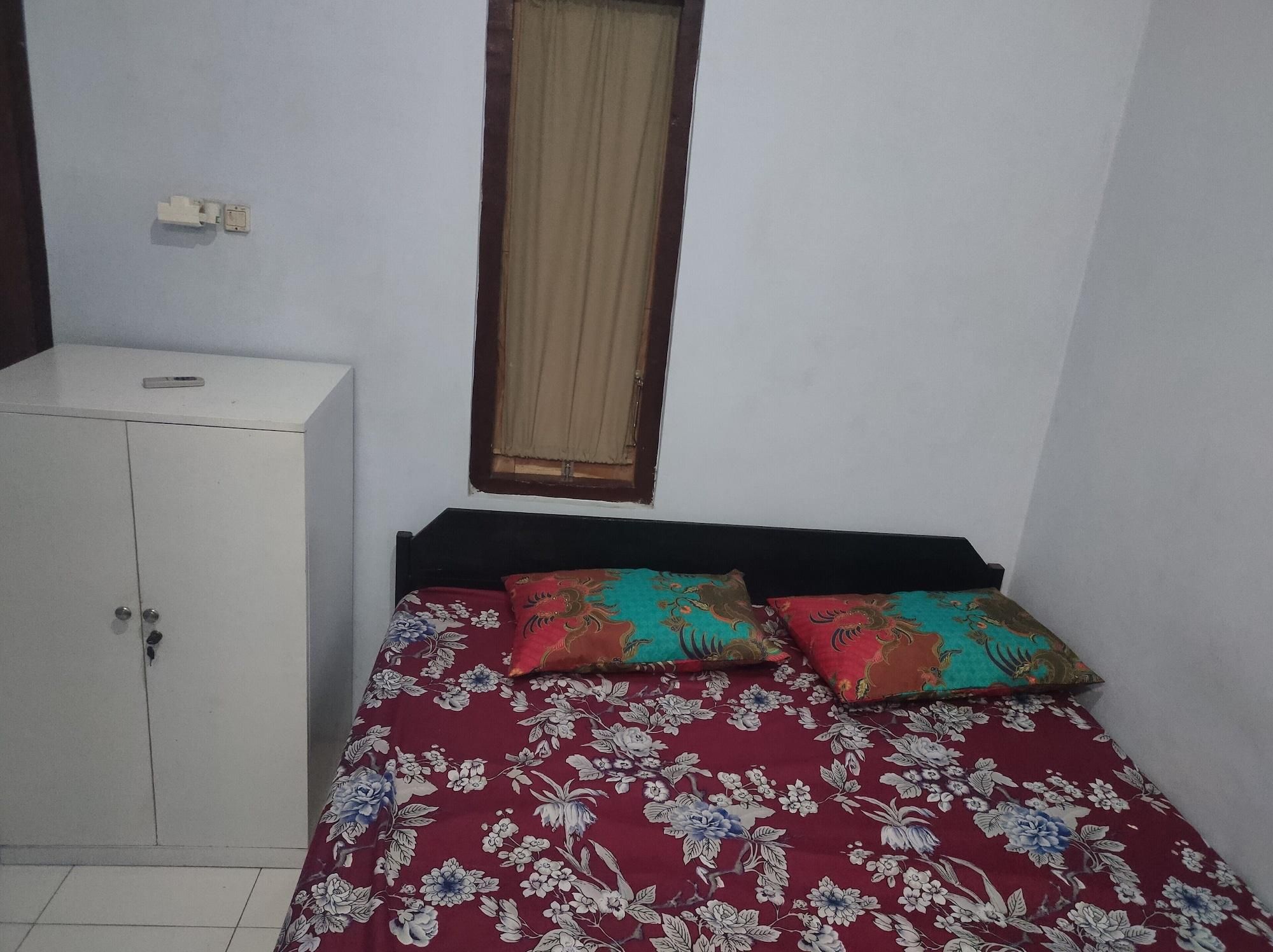 Een kleine kamer met een bed, een kledingkast en een raam met gordijnen.