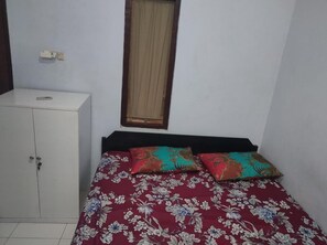 A small room with a bed, a wardrobe, and a window with curtains. - Homestay Wijaya Mulya By Zuzu (Borobudur)