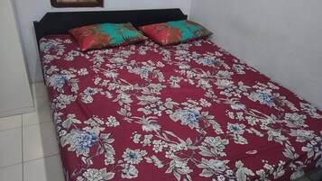 Een bed met een bloemenprint sprei en twee decoratieve kussens.