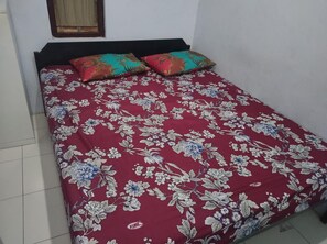 A bed with a floral bedspread and two decorative pillows. - Homestay Wijaya Mulya By Zuzu (Borobudur)