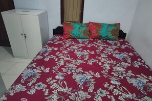 Una habitación con cama, armario y ventana con cortina.