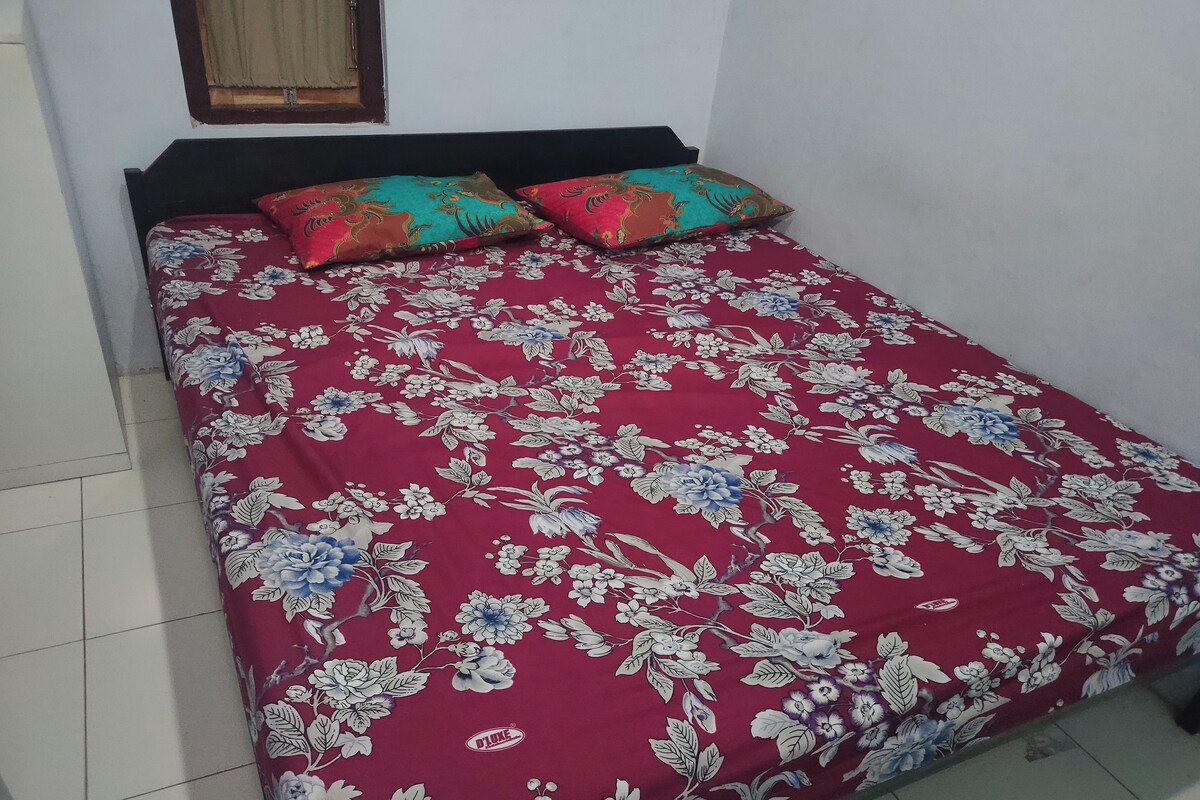 Una cama con colcha estampada y dos almohadas.