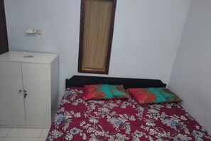 Una habitación pequeña con una cama individual, un armario y una ventana con cortina.