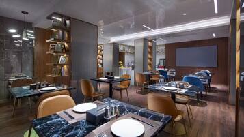 Un comedor moderno con mesas de mármol, sillas de madera e iluminación colgante.